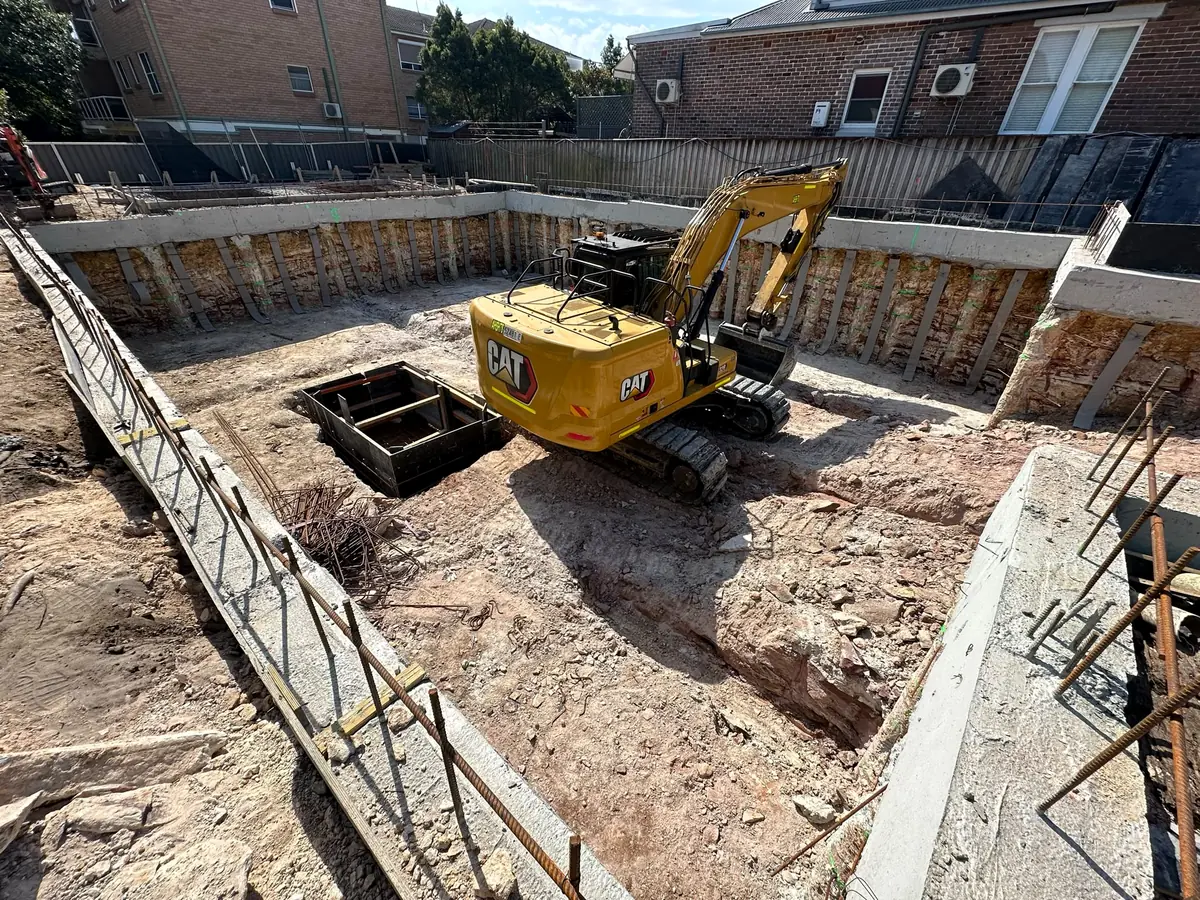 Excavator working inside a capped pile wall