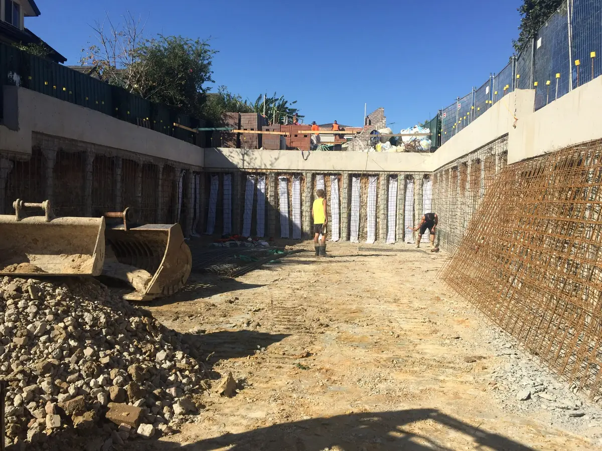 Mesh pinned along a piled wall before spraying